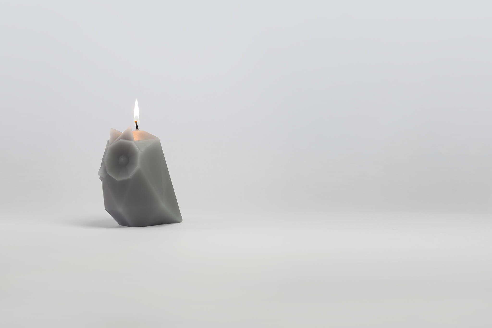 Ugla, the grey owl-shaped pyropet candle with a burning wick. 